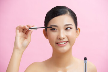Fototapeta premium Beautiful woman mascara applying makeup natural portrait beauty concept over pink background