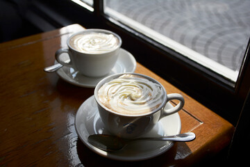 斜陽の当たったカフェの窓際。二つのウインナーコーヒー。