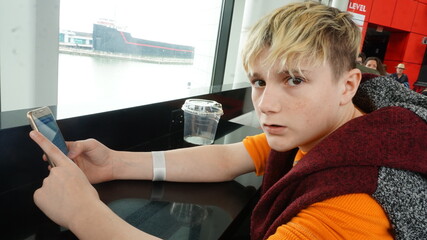 Defiant Blond Teen Using Cell Phone at Counter