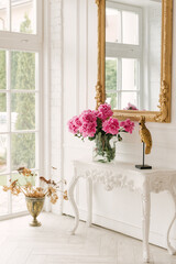 A bouquet of fresh pink peonies in a transparent vase in a luxurious interior