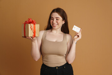 Young ginger woman smiling while posing with gist box and credit card