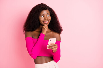 Photo of minded lady hold telephone finger chin look empty space wear cropped top isolated pink color background