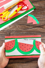 The child is holding summer birthday card with watermelons with birthday greetings. Handmade....