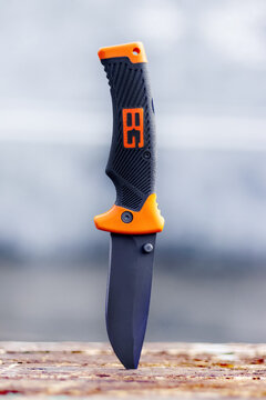 Ukraine, Khmelnytsky region, April 2021. Hunting knife stuck in a board on a dark background