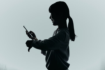 スマートフォンを操作する女性のシルエット