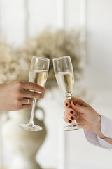 2 glasses of sparkling wine in the hands of a man and a woman on a light background