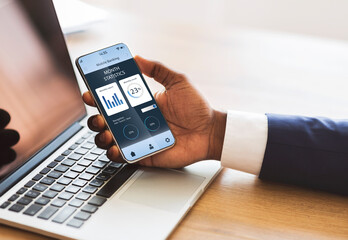 African american businessman hand holding mobile phone with trading app
