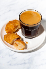 black coffee in a glass and mini croissant, vertical top view