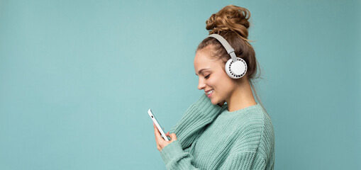 Panoramic Side-ptofile closeup photo of beautiful young woman wearing stylish casual outfit isolated over colorful background wall wearing white wireless headphones and listening to music and using