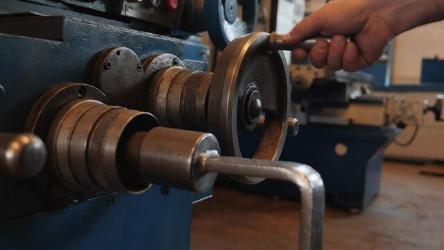 Male hand adjusting industrial machine rotating a wheel - close up, camera push forward