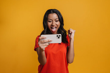 Black excited woman making winner gesture while playing game on cellphone