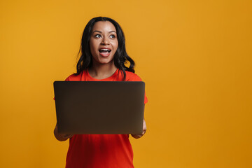 Young black woman smiling while posing with laptop