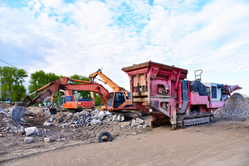 Mobile Stone Jaw crusher machine and excavator during crushing concrete on construction site....