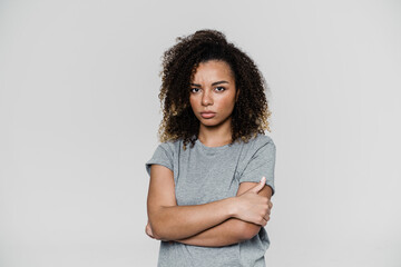 An offended woman looking at the camera with her crossing arms while standing in the studio