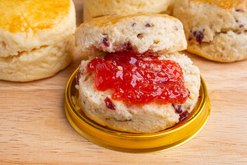 Scones traditional English delicious freshly baked homemade with strawberry jam on a wooden table. Close-up photo. Dessert, beverage, and relaxation concept