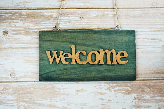 Welcome sign hanging on wooden background