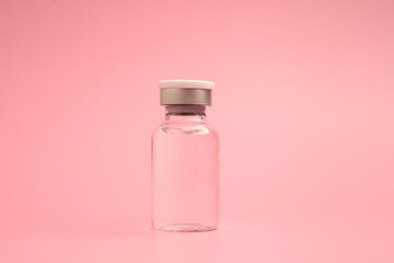 A vaccine in a glass bottle on a light pink background. Vaccine for immunization, and treatment from virus infection. Side view. Concept of medical and healthcare