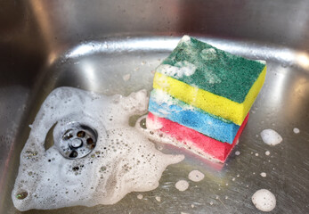 Sponge with detergent and foam while washing the sink in the kitchen. Wash dishes and plumbing....