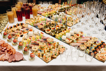 Beautifully decorated catering banquet table with burgers, profiteroles, salads and cold snacks. Variety of tasty delicious snacks on the table
