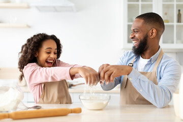 Happy afro man and his daughter preparing dough