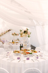 Luxury wedding dinner in a large beautiful tent, beautiful decor for the wedding of the white hall decorated with flowers