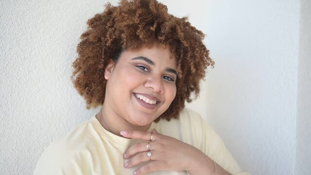 Beautiful happy smiling curvy plus size African black woman afro hair with make up posing in beige t-shirt on white background. Body imperfection, body acceptance, body positive and diversity concept.