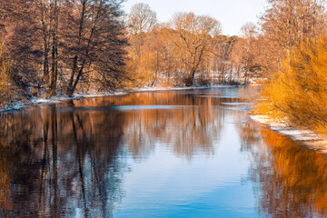 River flowing slowly during a winter day with some snow on the sides of the water