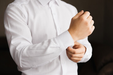 wedding photo, male groom fastens cufflinks on his shirt