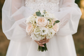 Wedding bouquet in pastel colors in the hands of the bride of roses, eustoma, peonies, carnations and eucalyptus.