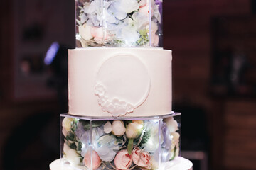 Luxury large white multi-tiered cake with illuminated glass tiers, decorated with fresh flowers