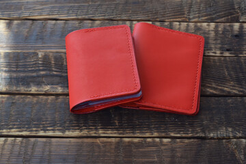 Red handmade business card holder and passport cover made of genuine leather on a wooden table.