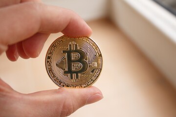 Man is holding golden bitcoin in his hand. The popular cryptocurrency is bitcoin.