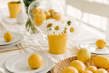 Beautifully served spring summer white table with lots of lemons and chamomile.