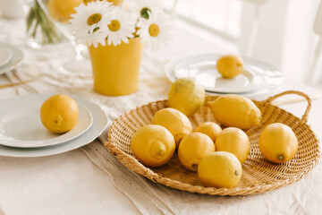 Beautifully served spring summer white table with lots of lemons and chamomile.
