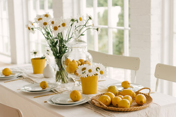 Beautifully served spring summer white table with lots of lemons and chamomile.