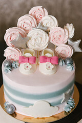 A beautiful cake made of natural ingredients with children's shoes in pink and gray colors for a girl's birthday or christening