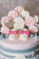 A beautiful cake made of natural ingredients with children's shoes in pink and gray colors for a girl's birthday or christening