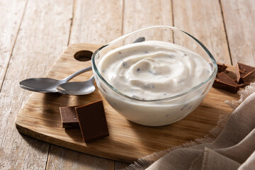 Stracciatella yogurt in transparent bowl on wooden table	