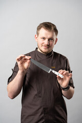 Chef in a uniform jacket, demonstrates a professional chef's knife