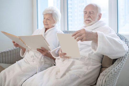 Mature couple in white robes choosing procedures in a spa center