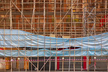 Buiding wrapped in traditional Chinese scaffolding made of bamboo in Hong Kong.