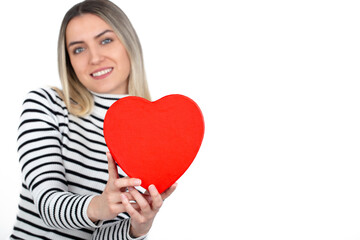 Woman holding a small gift box in a gesture of giving. Female hands holding red heart shape.