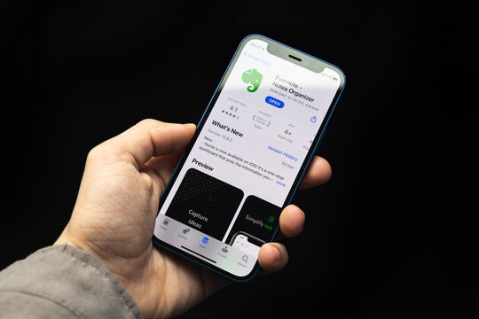 Kharkov, Ukraine - April 20, 2021: Hand holds iPhone with Evernote app, icon application close-up on a black background