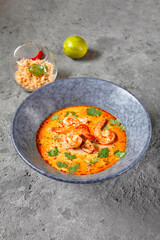 Tom Yum or Tom Yam Soup - Hot and Sour Thai Soup cooked with Shrimp. Thai Authentic Traditional Dinner. Soup in Blue Bowl on Dark Grey Table. Street Asian Food.