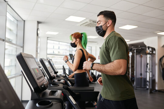 Two people exercising on treadmills social distancing and wearing masks - Powered by Adobe