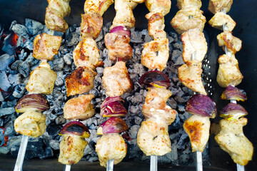 Marinated shashlik with onion preparing on a barbecue grill over charcoal. Top view