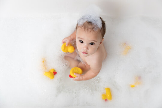 Cute Baby Girl In Bubble Bath Playing With Rubber Ducks