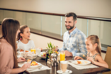 Smiling family sitting at the table and looking happy