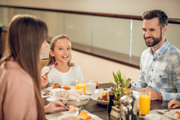 Smiling family sitting at the table and looking happy