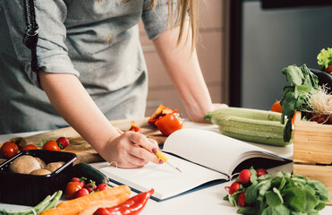 Unrecognizable woman is looking for recipes in cookbook.
Female chef reading recipes in book and...